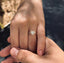 Close-up of a hand showcasing a heart-shaped diamond ring set in gold, called 'Mon Amour', emphasizing the ring's elegant design and brilliant sparkle.