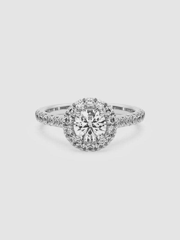 video of the Parasol ring highlighting the round-cut center diamond encircled by a halo of smaller diamonds on an 18k white gold band.